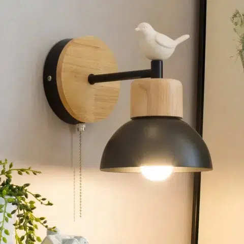 Sur un mur on voit une applique murale noire style nordique ornée d'un oiseau blanc.