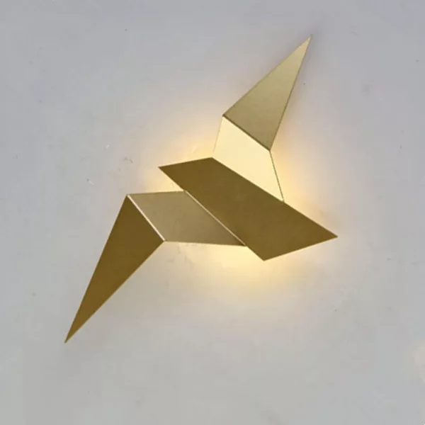 Sur un fond blanc on voit une applique murale dorée en forme d'oiseau style origami.