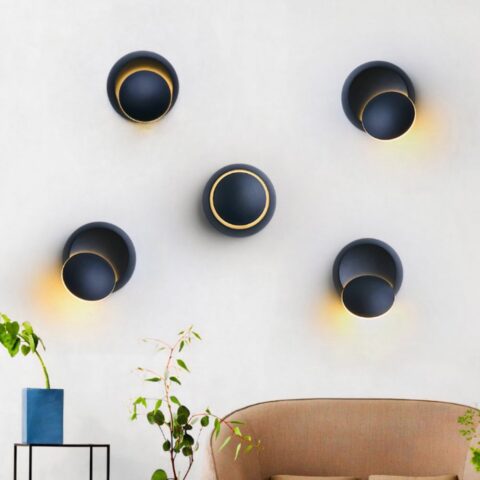 on voit sur un mur de salon blanc plusieurs appliques murale rotative led de couleur noir