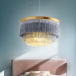 Suspension bohème ronde à franges au-dessus d'un lit dans une chambre bleue