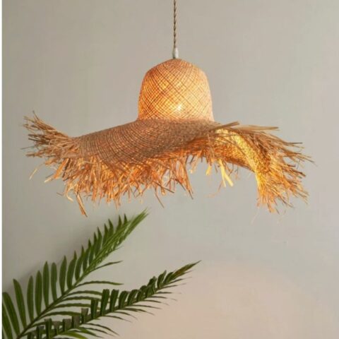on voit sur un fond gris une suspension en forme de chapeau de paille fait à la main en raphia