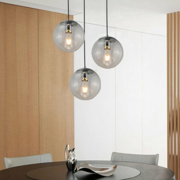Suspension globe en verre design moderne de couleur noire présentée 3 fois au-dessus d'une table à manger
