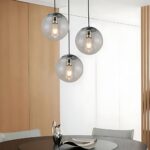 Suspension globe en verre design moderne de couleur noire présentée 3 fois au-dessus d'une table à manger