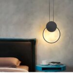 Suspension LED design minimaliste anneau noir au dessus d'une table de chevet pres d'un lit