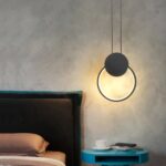 Suspension LED design minimaliste anneau noir au dessus d'une table de chevet pres d'un lit