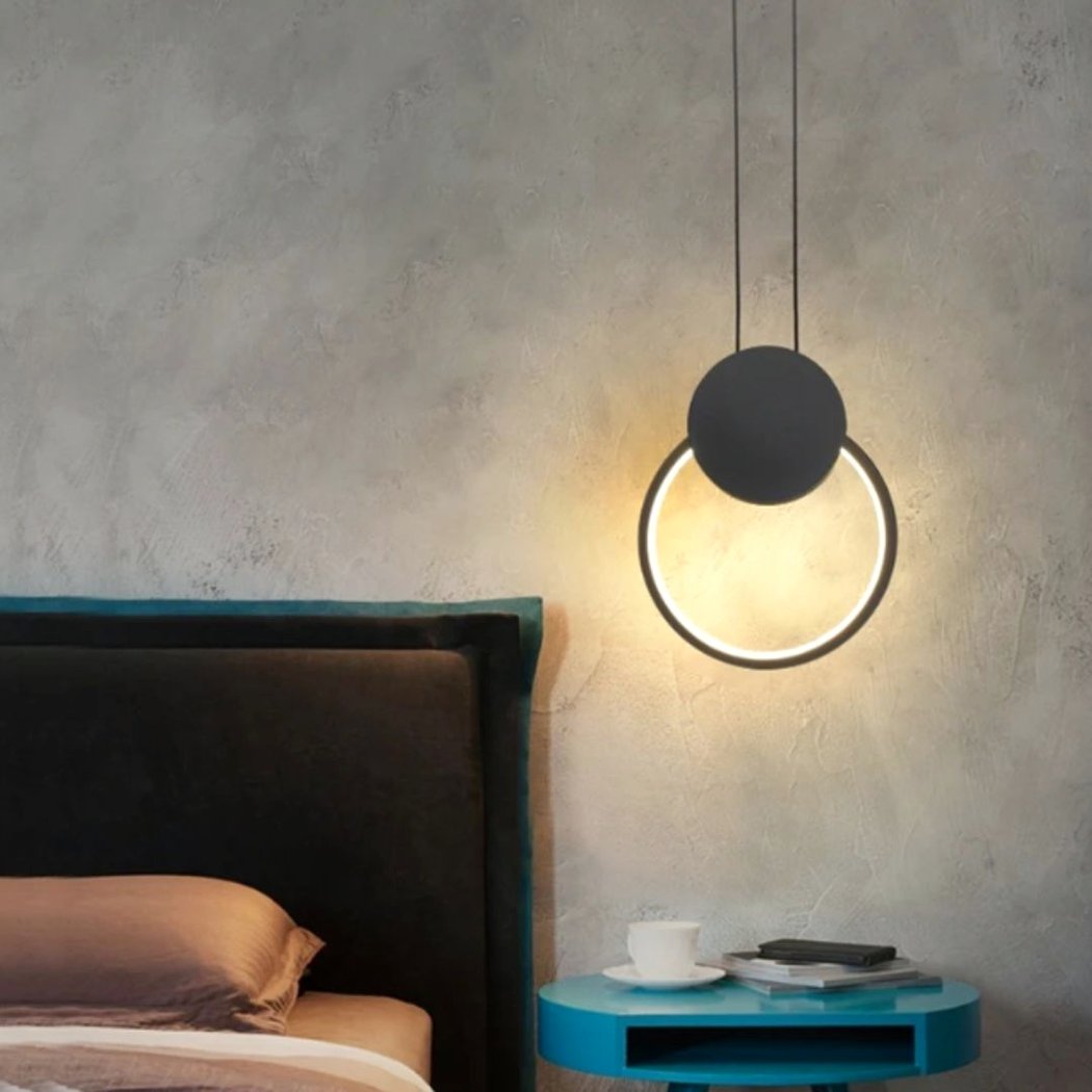 Suspension LED design minimaliste anneau noir au dessus d'une table de chevet pres d'un lit