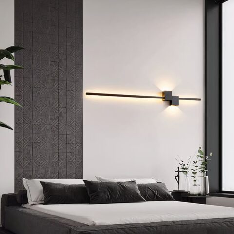 Applique mural tête de lit design et moderne de couleur noir avec lumière jaune, au dessus d'un lit