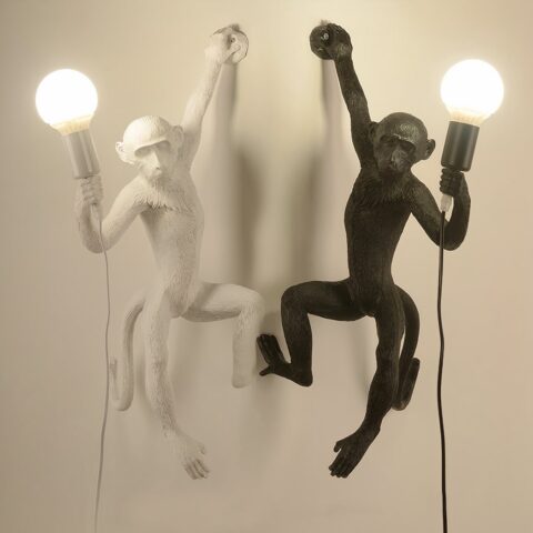 Sur un fond blanc on voit deux appliques murales en forme de singe. Celle de droite est noire et celle de gauche est blanche.