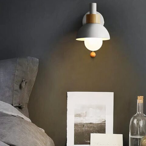 Applique murale de chambre avec interrupteur, de couleur blanche au dessus d'une table de chevet