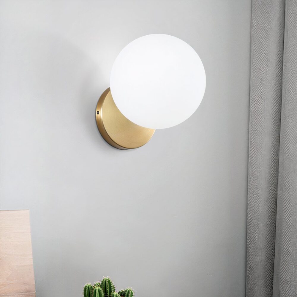 Sur un fond blanc on voit une applique murale dorée et blanche en forme de boule de verre allumée.