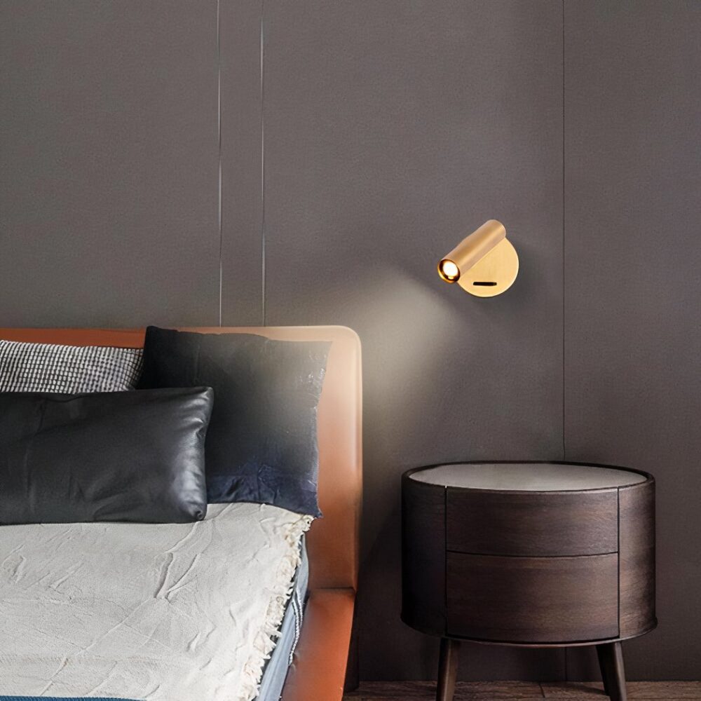 Applique murale en laiton réglable, de couleur dorée, à côté d'un lit au dessus d'une table de chevet
