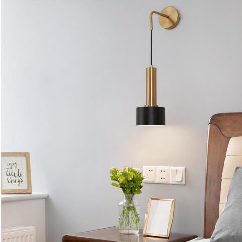 Applique murale en laiton style lanterne, de couleur noir et doré suspendu à côté d'un lit