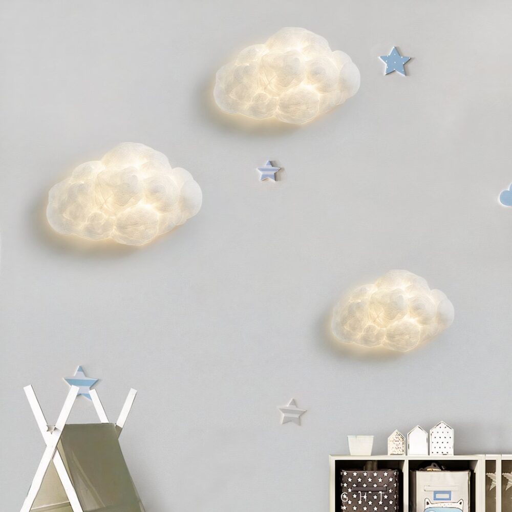 Sur un mur blanc on voit trois appliques murales en forme de nuage blanches allumées.