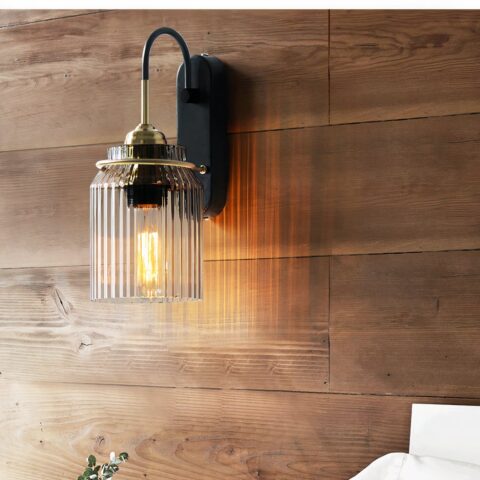 Applique murale en verre style industriel, avec support en métal noir, contre un mur en bois