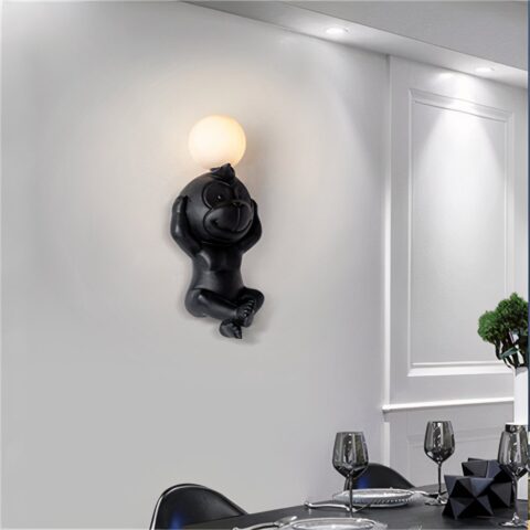 Sur un mur bleu foncé on voit au milieu accrochée, une applique murale en forme de singe blanche allumée.