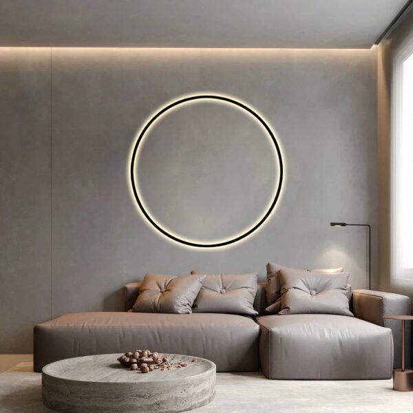 Dans un salon sur le mur au-dessus du canapé gris on peut voir une applique murale en forme de cercle noir.