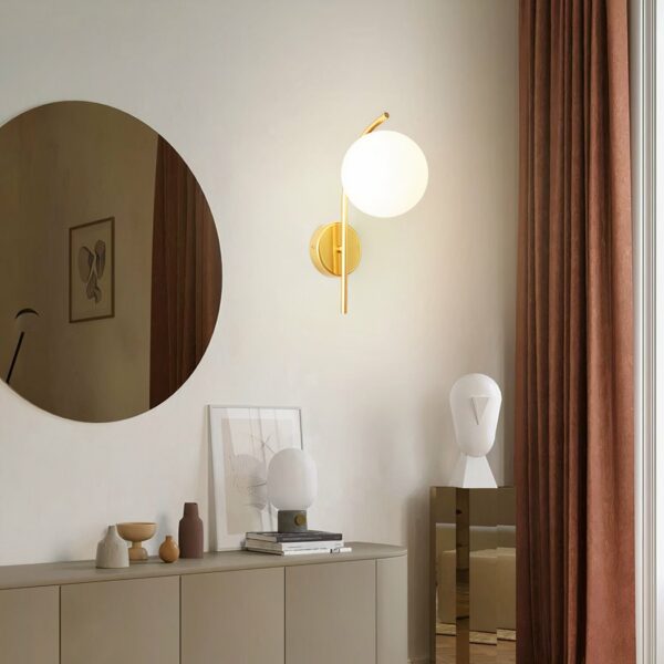Dans un salon on voit accrochée au mur une applique murale au style moderne dorée.