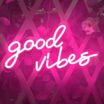 On voit une applique murale néon rose avec l'écriture good vibes allumée.