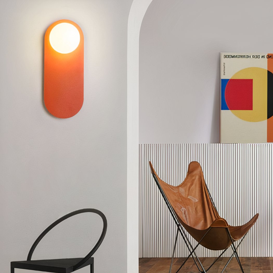 Applique murale orange design, dans une pièce épurée à côté d'un tableau d'artiste et une chaise