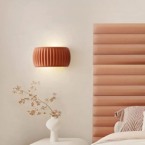 Applique murale orange en résine, à côté d'un lit