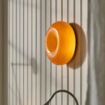 Applique murale orange et ronde, positionné sur un mur