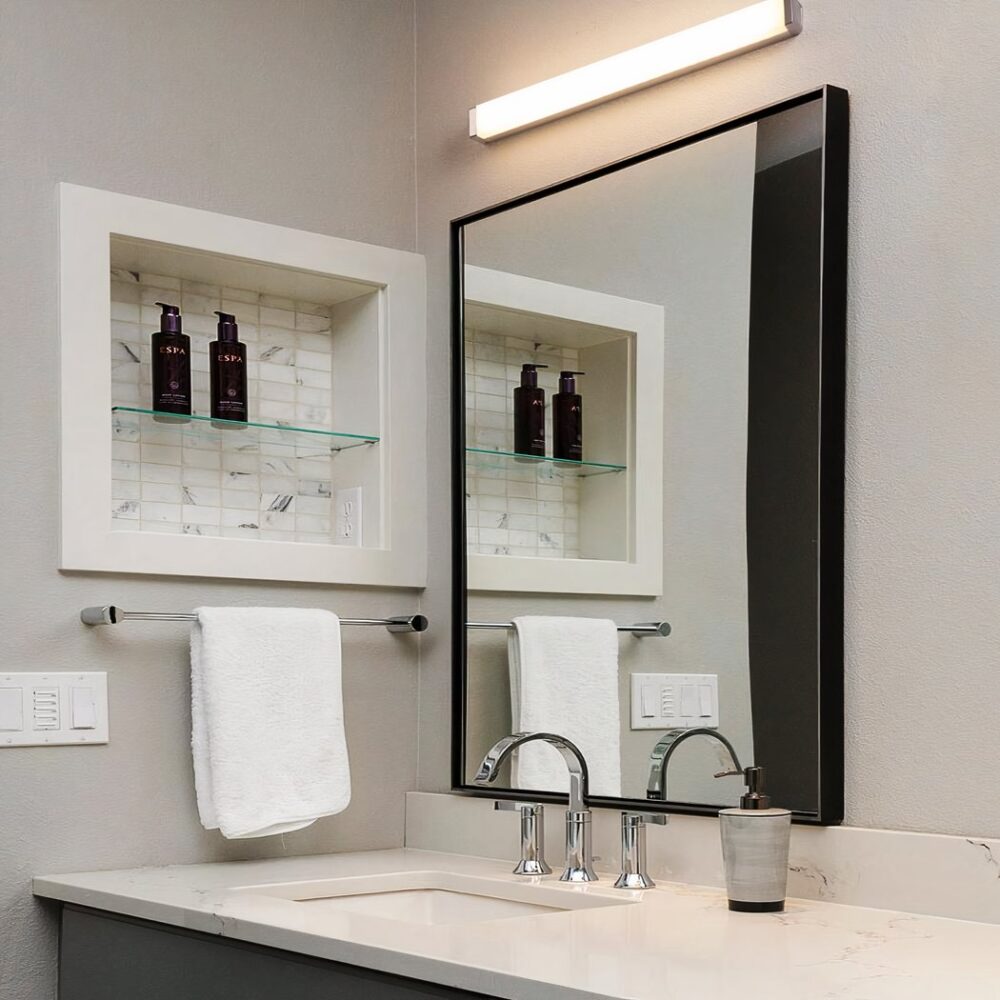 Applique murale salle de bain longue sans perforation noire présentée installée au dessus d'un miroir