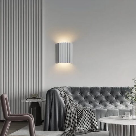 Applique murale scandinave strillée éclairage double blanc présentée installée à une mur au dessus d'un canapé