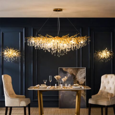 Lustre cuisine long et doré à design de gouttes d'eau sur fond bleu foncé avec une table et des fauteuils