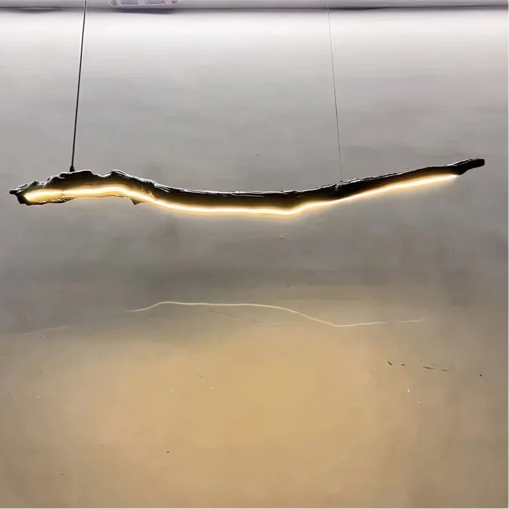 Lustre en bois flotté suspendu, avec une bande LED sur toute la longueur. En fond un mur gris.
