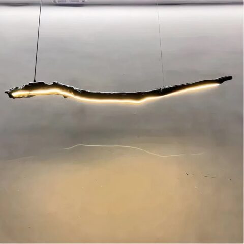 Lustre en bois flotté suspendu, avec une bande LED sur toute la longueur. En fond un mur gris.