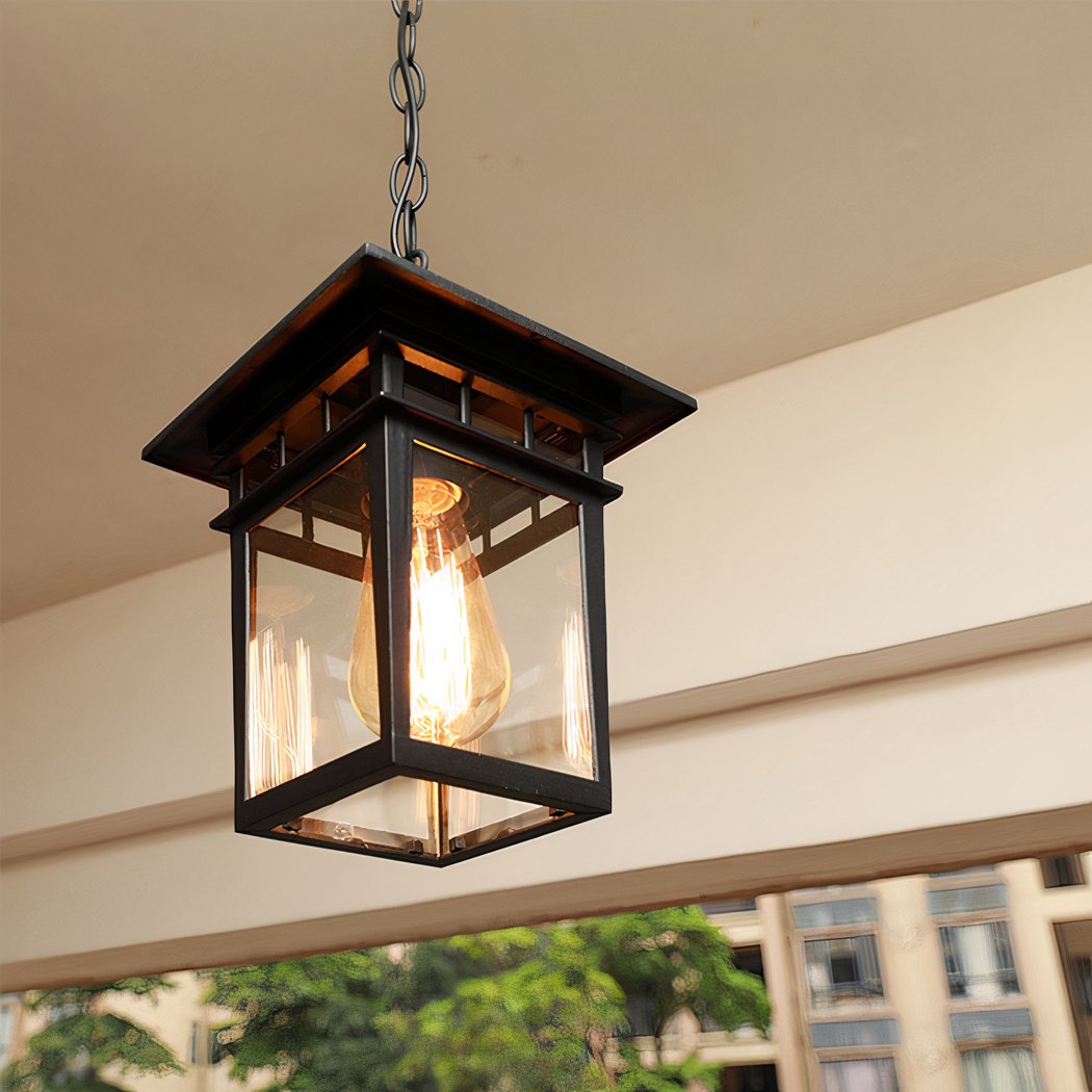 Accrochée au plafond d'une terrasse on peut voir un lustre extérieur style lanterne japonaise noire allumé.