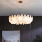 lustre feuille LED Rond avec des pampilles en verre blanc en forme de feuille devant un mur gris