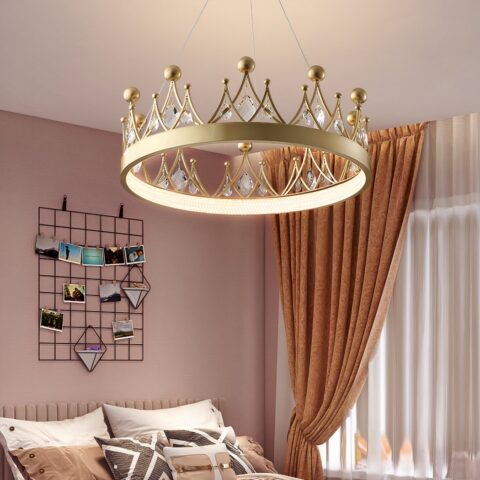 Lustre pour chambre de bébé en forme de couronne de couleur doré, avec des pierres en cristal sur celle ci, dans une chambre aux murs roses