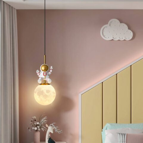 Suspension de chambre pour bébé en forme de lune jaune avec astronaute dessus dans une chambre rose