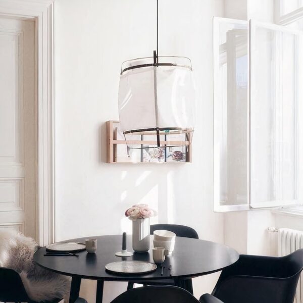 Suspension en lin blanc et design, dans une salle à manger, au dessus d'une table ronde noire