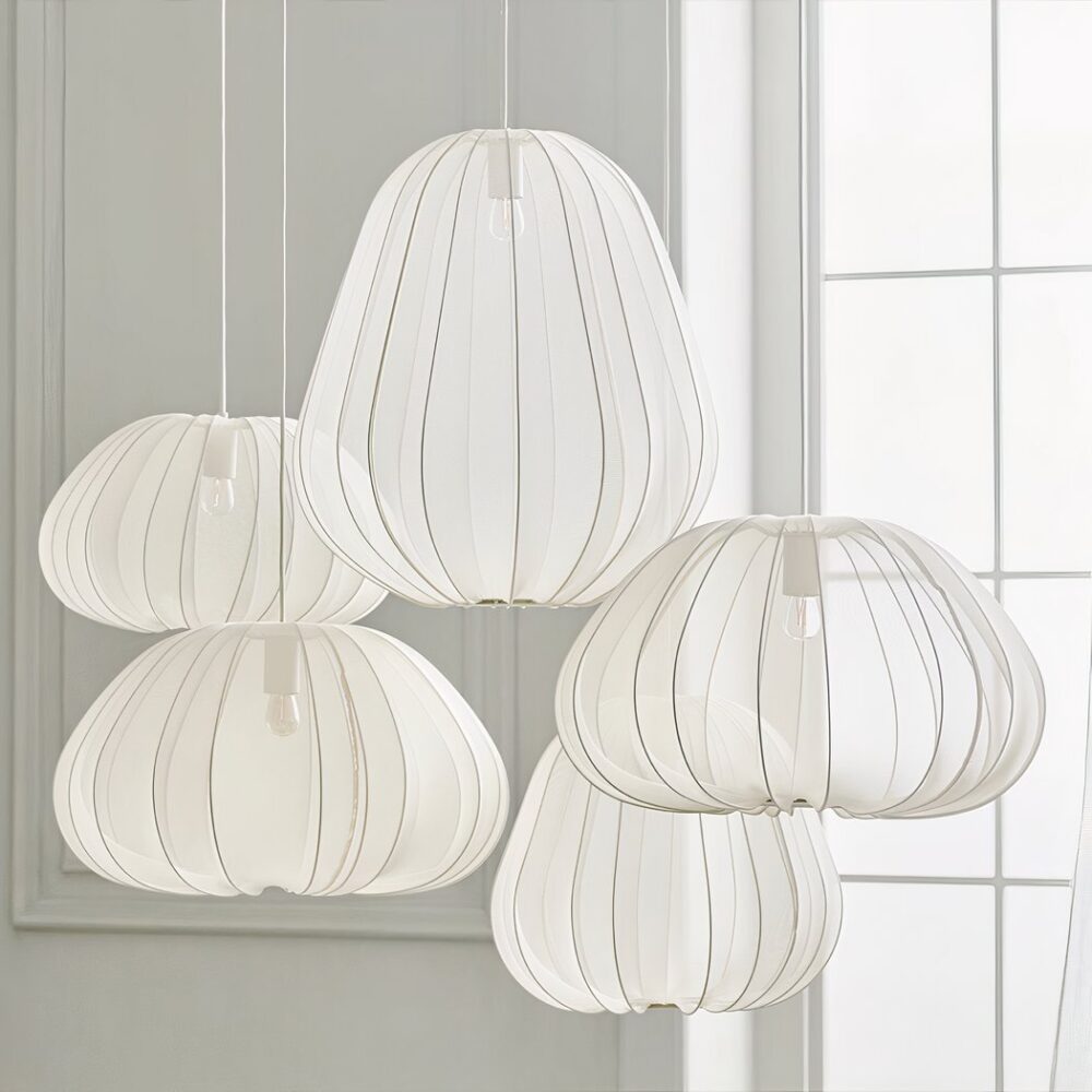 Quatre suspensions en tissu blanc plissé de formes différentes contre un mur gris