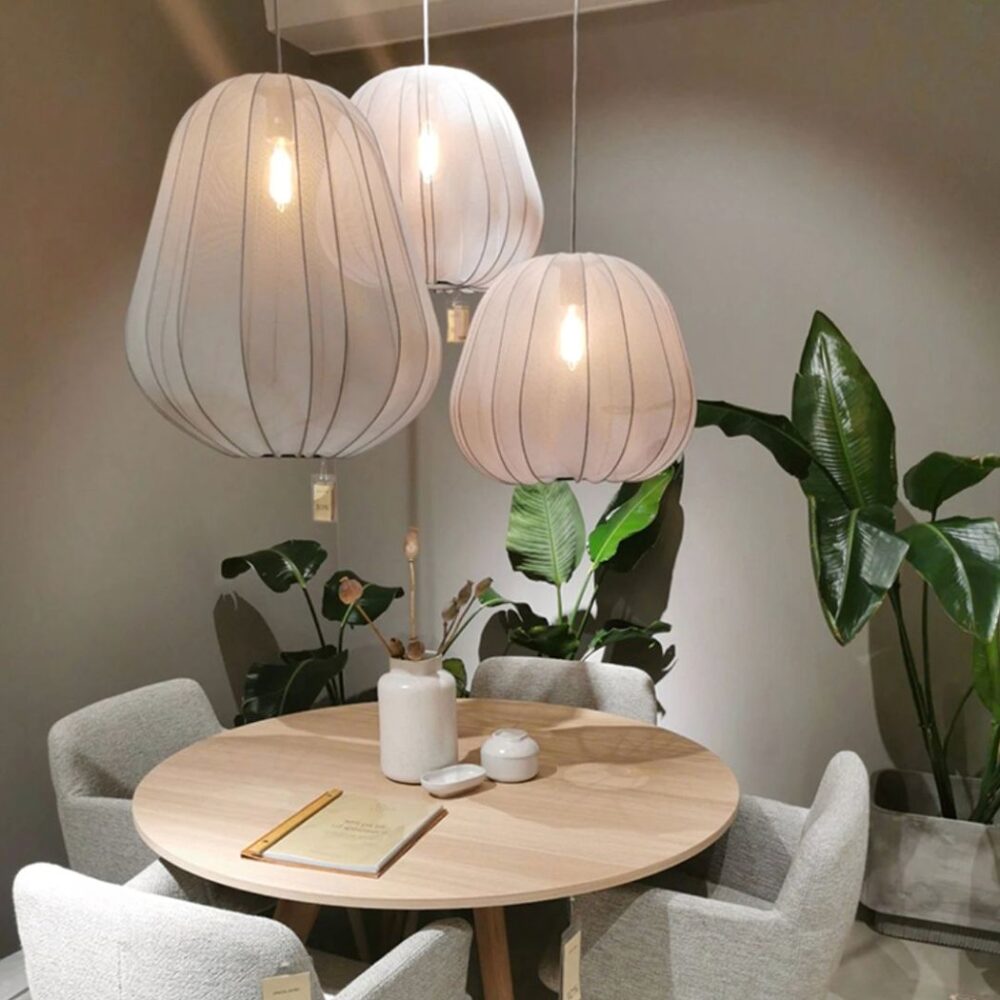 Trois suspensions en tissu blanc plissé au-dessus d'une table ronde entourée de plantes