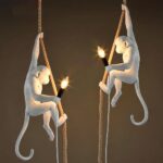 Suspension singe blanc se tenant à une corde présentée en deux exemplaires se faisant face