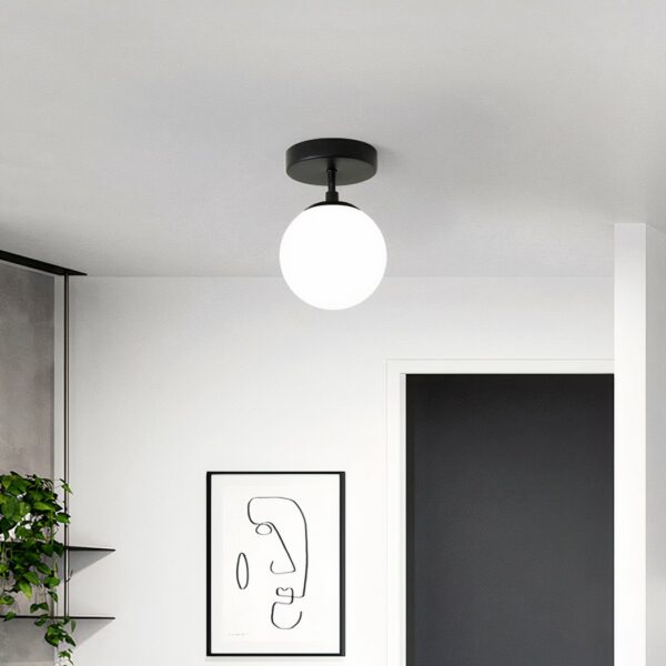 Suspension salle de bain LED ronde en verre et fer sur fond gris avec un tableau