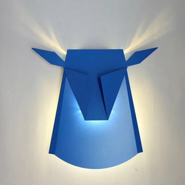 Applique murale bleu LED en forme de cerf en métal. Au design minimaliste. La lumière diffuse les cornes du cerf au mur. sur un mur blanc.
