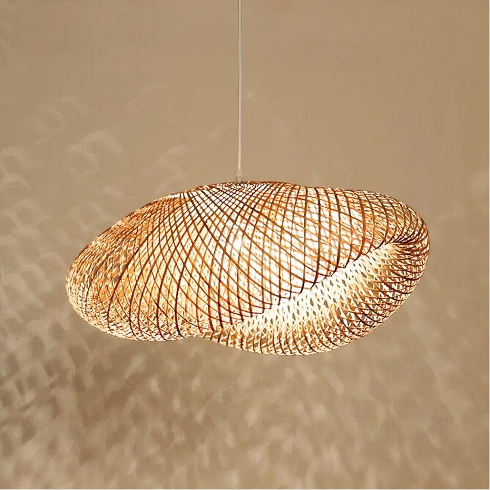 Lustre en bambou à grand abat-jour aéré au design moderne. Avec l'ampoule allumée, qui projette des ombres sur le mur beige derrière le lustre.