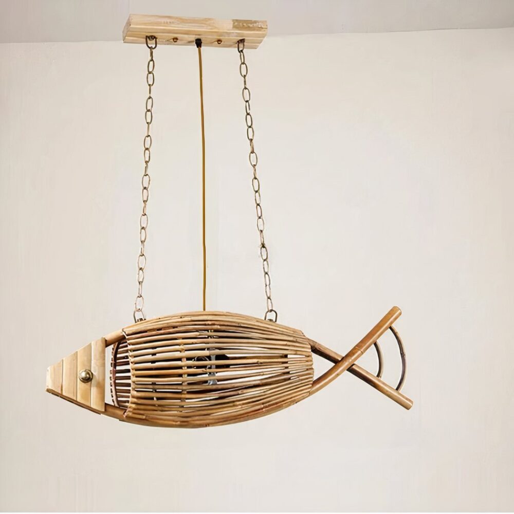 Lustre en bois en forme de poisson, suspendu par deux chaines à chaque extrémité. Relier à un socle rectangulaire en bois. Derrière on voit un mur beige.