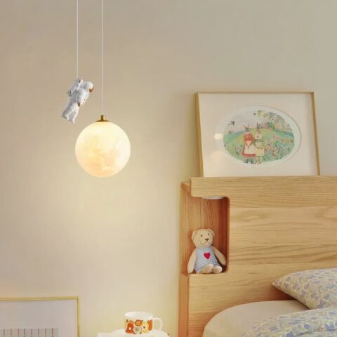 Lustre de style nordique en résine avec astronaute sur fond beige avec un lit à droite