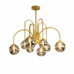 Lustre doré en métal avec 8 bras qui donne l'impression de feu d'artifices, avec 8 boules en verre grises et les ampoules allumées dans chaque boule. Sur un fond blanc.