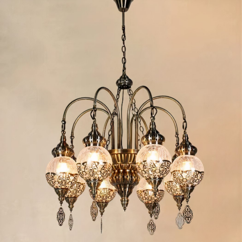 Lustre marocain en métal et en boules de verre craquelé. Composé de 8 boules accrochées au lustre par des bras recourbés. Et chacune habillé de genre de broderies métalliques. Sur un fond beige.