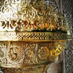 Gros plan sur la couronne supérieure en laiton ajouré à motifs arabes du lustre
