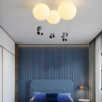 Lustre suspendu avec trois pandas en acrylique sur fond bleu avec un lit
