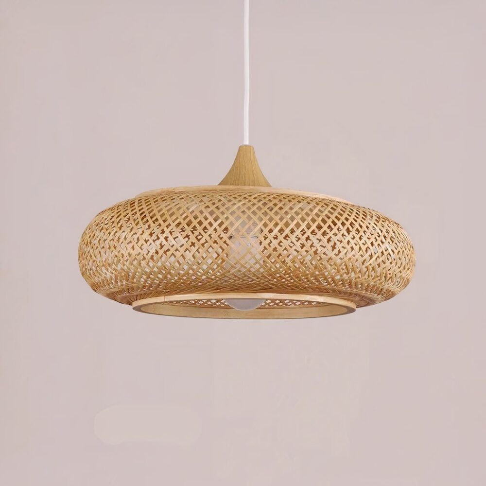 Lustre suspendu de forme ronde et plate, en babou tressé. Sur un fond rose pâle.
