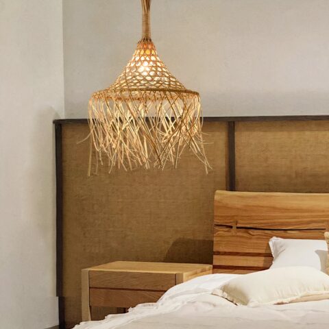 Lustre suspendu en paille et rotin fait main accroché au plafond et allumé, dans une chambre à coucher.