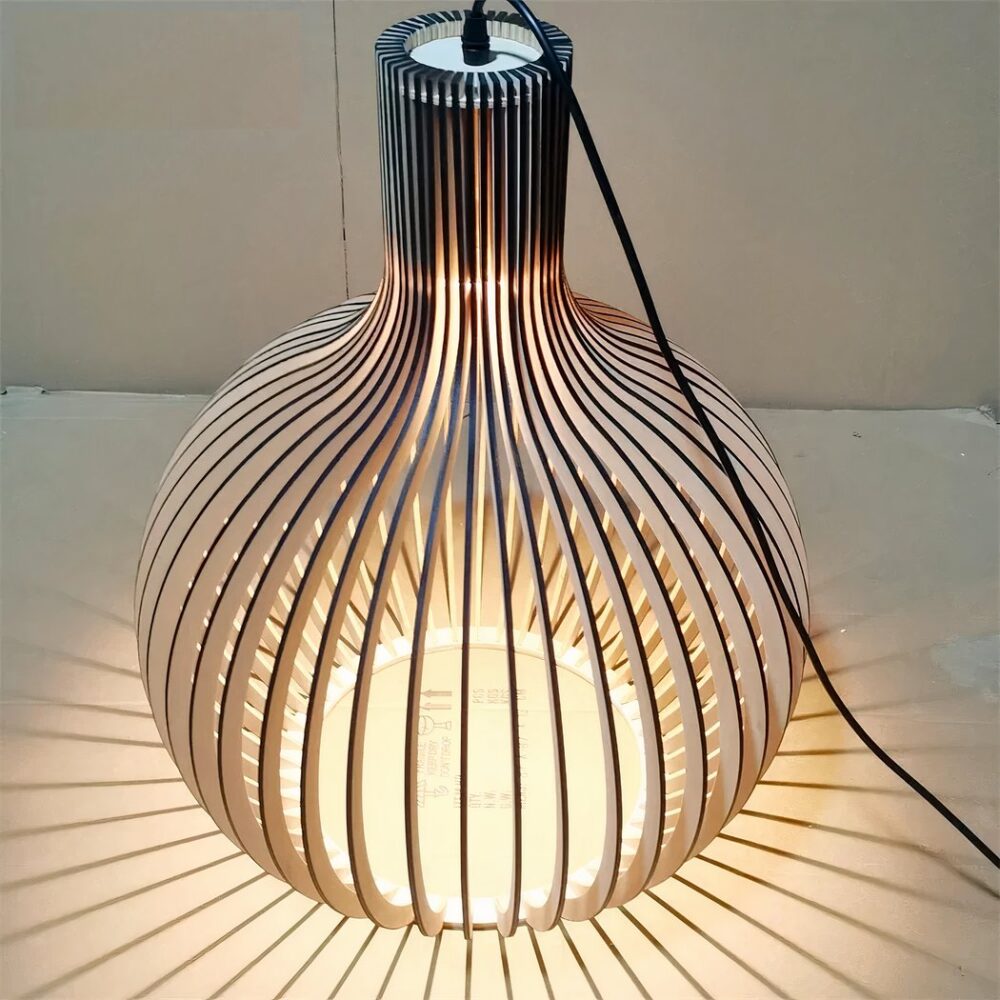 Lustre DIY en bois massif de bambou, assemblé et allumé, sur fond beige.